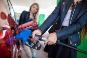 Happy friends refuel car in gas station. Holiday trip of friends